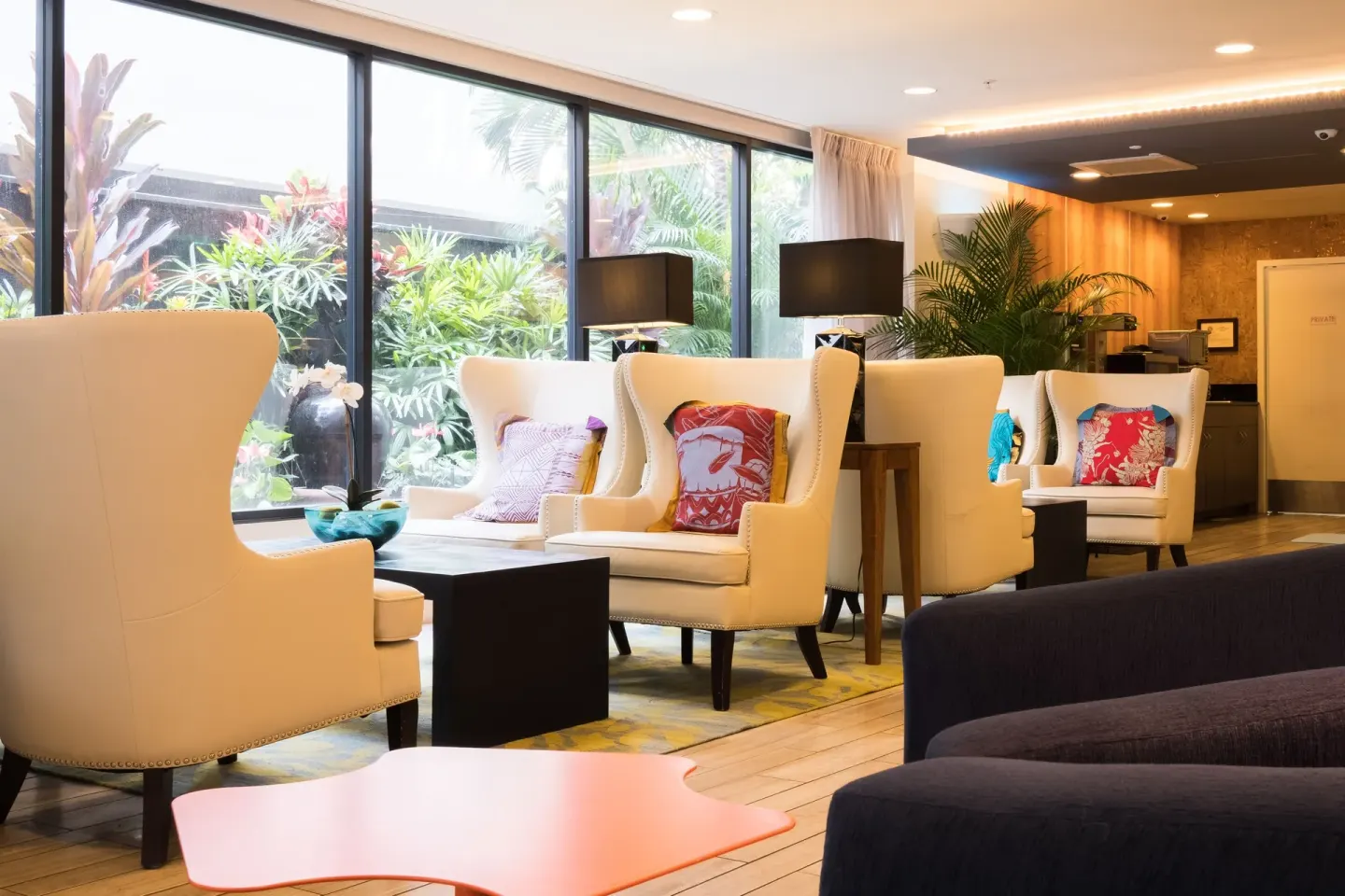 Lounge seating with wingback chairs and garden windows at Vive Hotel Waikiki.