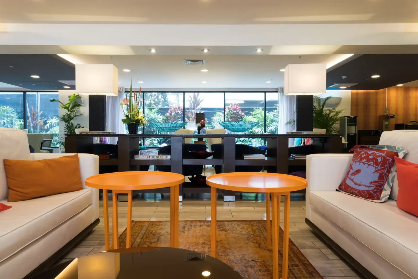 Lobby lounge with white sofas and orange tables at Vive Hotel Waikiki.