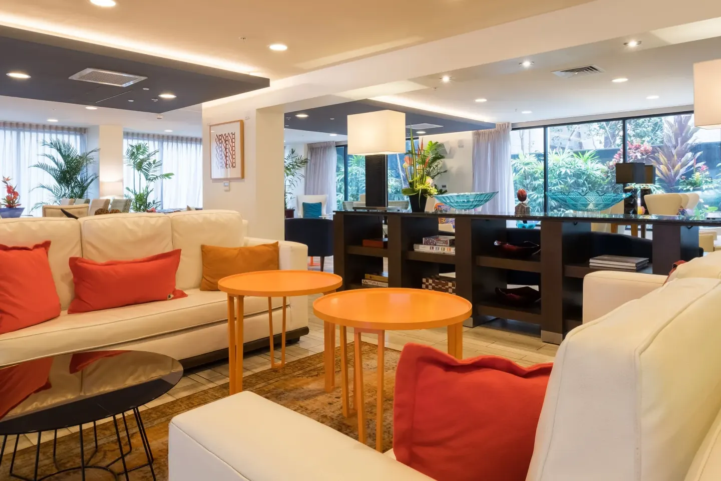 Lobby seating with white sofas and orange tables at Vive Hotel Waikiki.