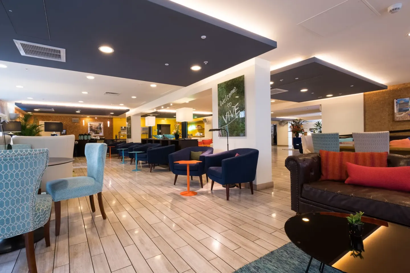 The lobby at Vive Hotel Waikiki has colorful chairs, sofas, tiled floors, and lounge tables.