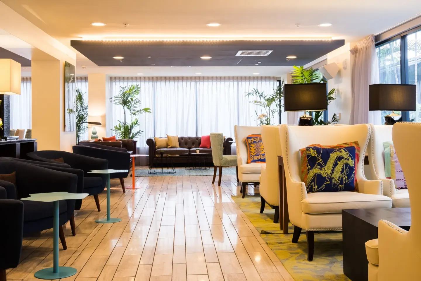 Open lobby seating with wingback chairs and sofas at Vive Hotel Waikiki.
