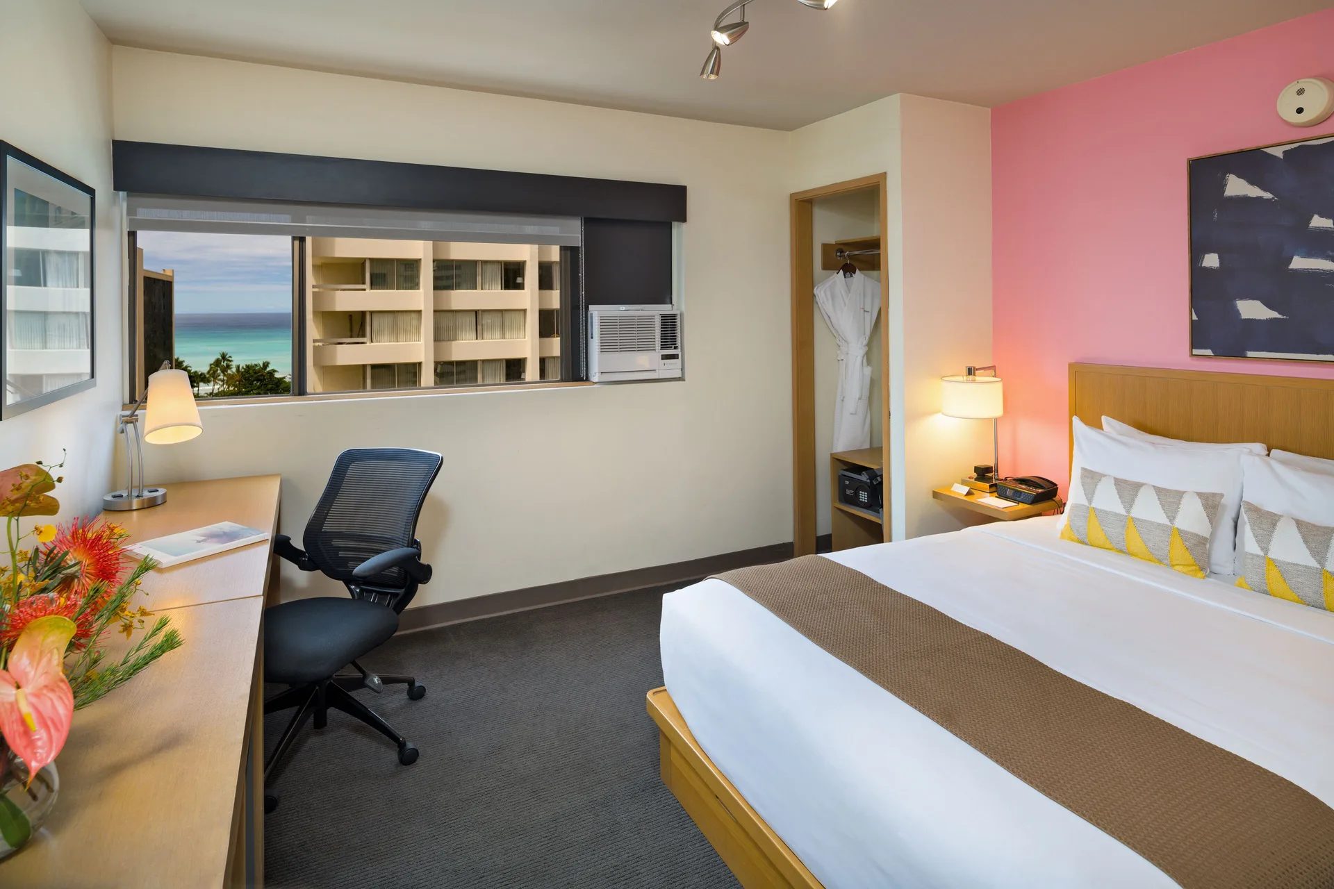 Deluxe Ocean View room with king bed, desk, and ocean glimpse at Vive Hotel Waikiki.