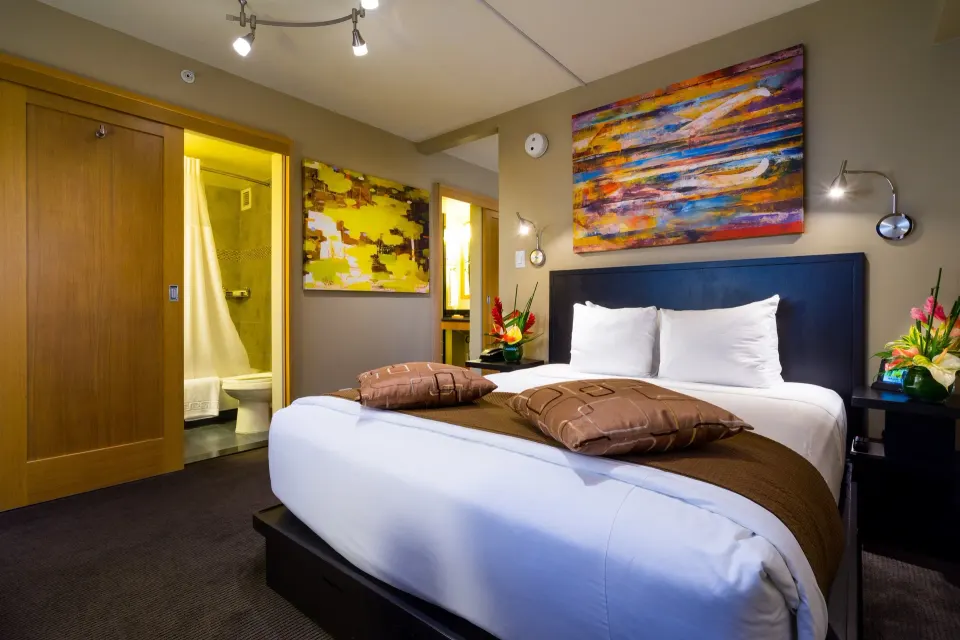 Bed and bathroom entrance in a Lifestyle Family Suite City View room at Vive Hotel Waikiki.