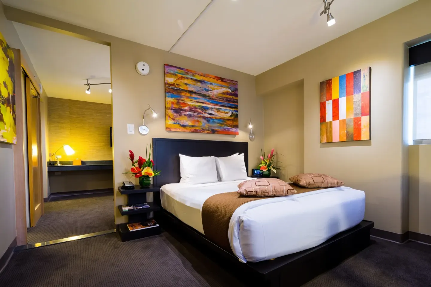 Bed and adjoining desk area in a Lifestyle Family Suite City View room at Vive Hotel Waikiki.