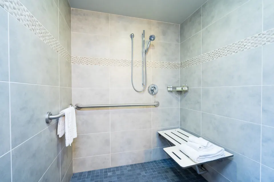 Roll-in shower with grab bars in a Lifestyle Jr. Suite bathroom at Vive Hotel Waikiki.