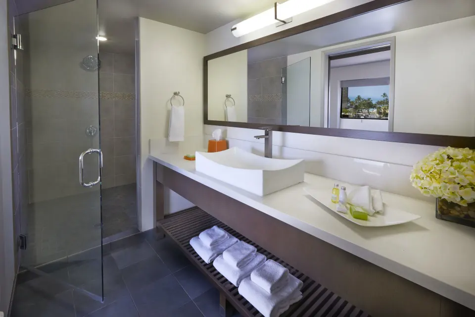 Bathroom vanity and glass shower in a Lifestyle Jr. Suite at Vive Hotel Waikiki.
