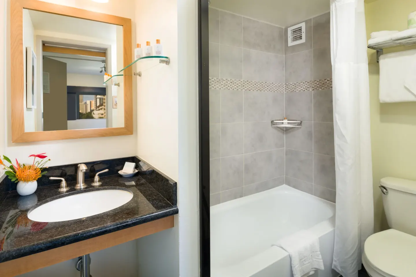 Standard Room bathroom with vanity, tub shower and towels at Vive Hotel Waikiki.