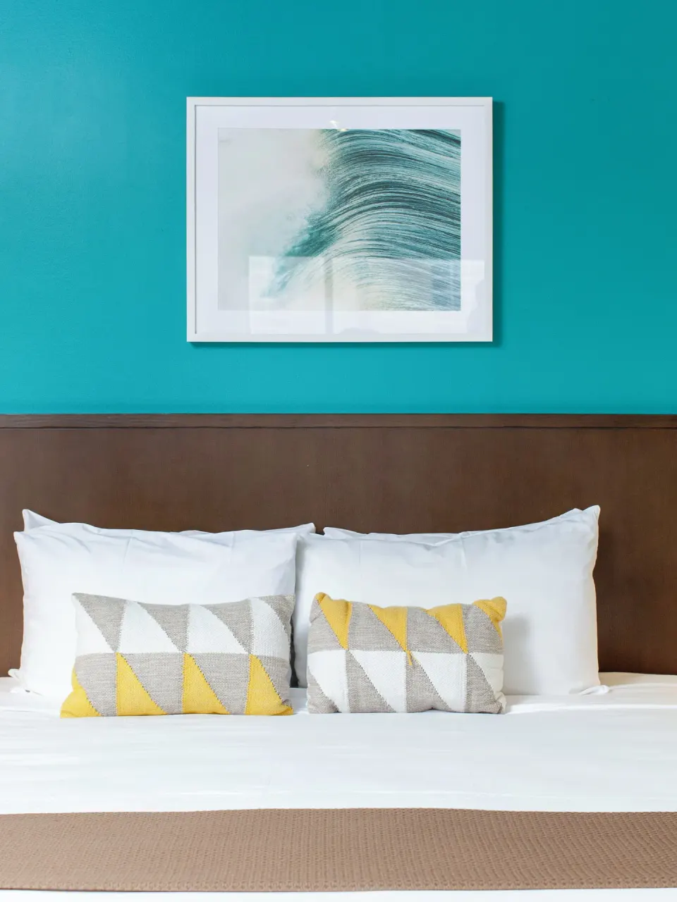 Close-up of the Standard Room bed and teal accent wall at Vive Hotel Waikiki.