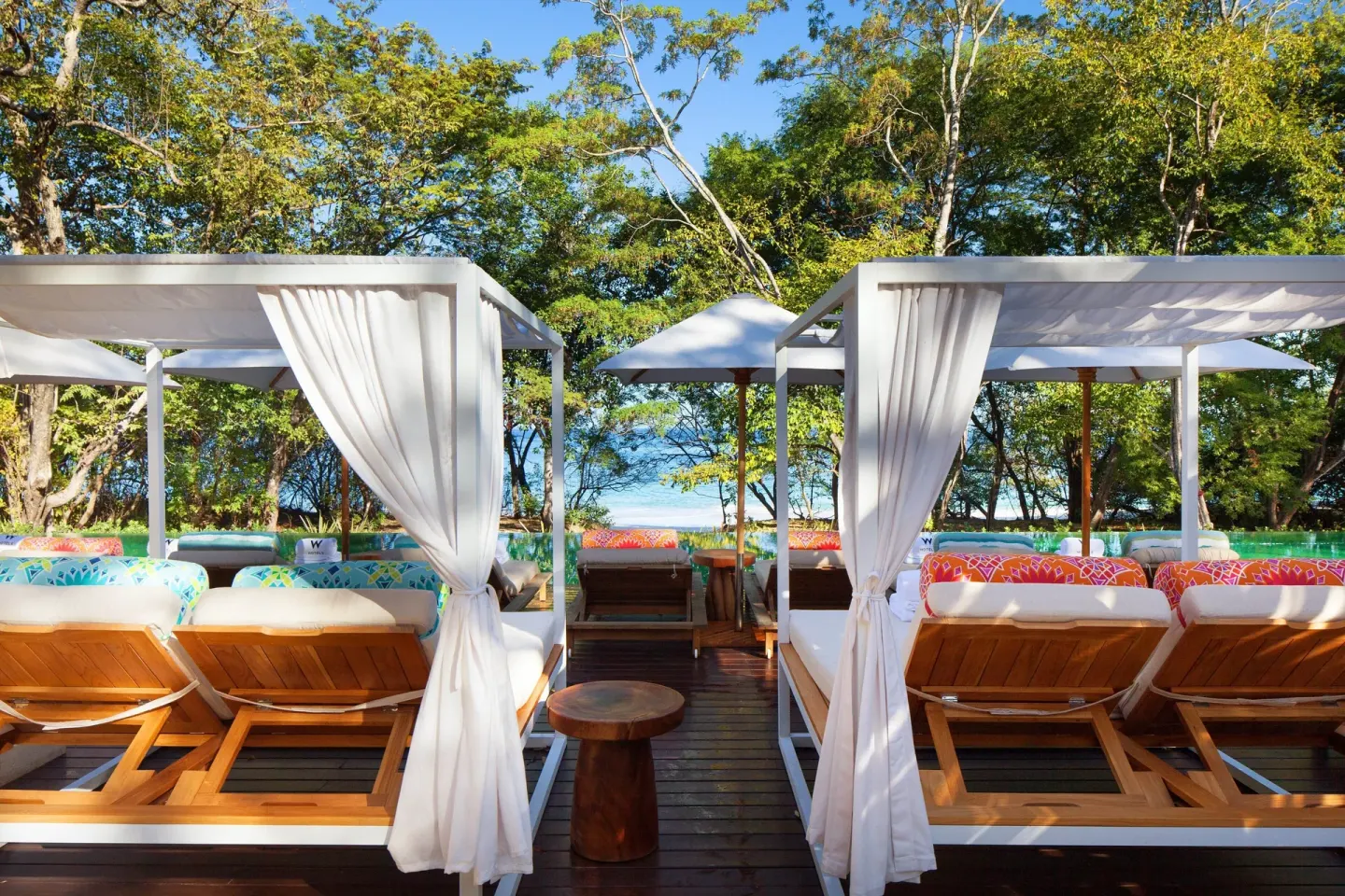 Beach cabanas with loungers, curtains, and ocean glimpses at W Costa Rica - Reserva Conchal.