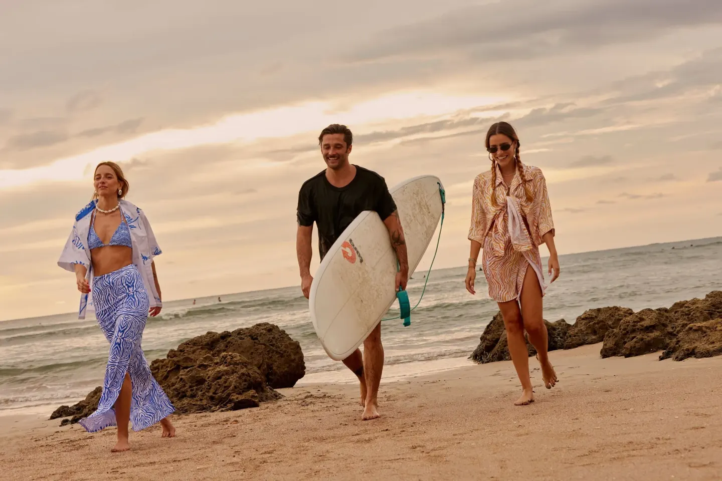 Three beachgoers walk by the surf and rocks at W Costa Rica - Reserva Conchal.
