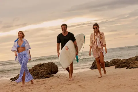 Three beachgoers walk by the surf and rocks at W Costa Rica - Reserva Conchal.