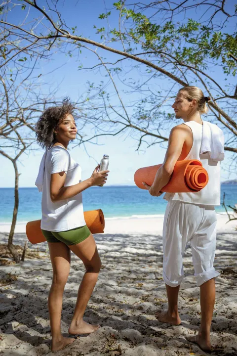 Guests carrying yoga mats on the beach at W Costa Rica - Reserva Conchal.