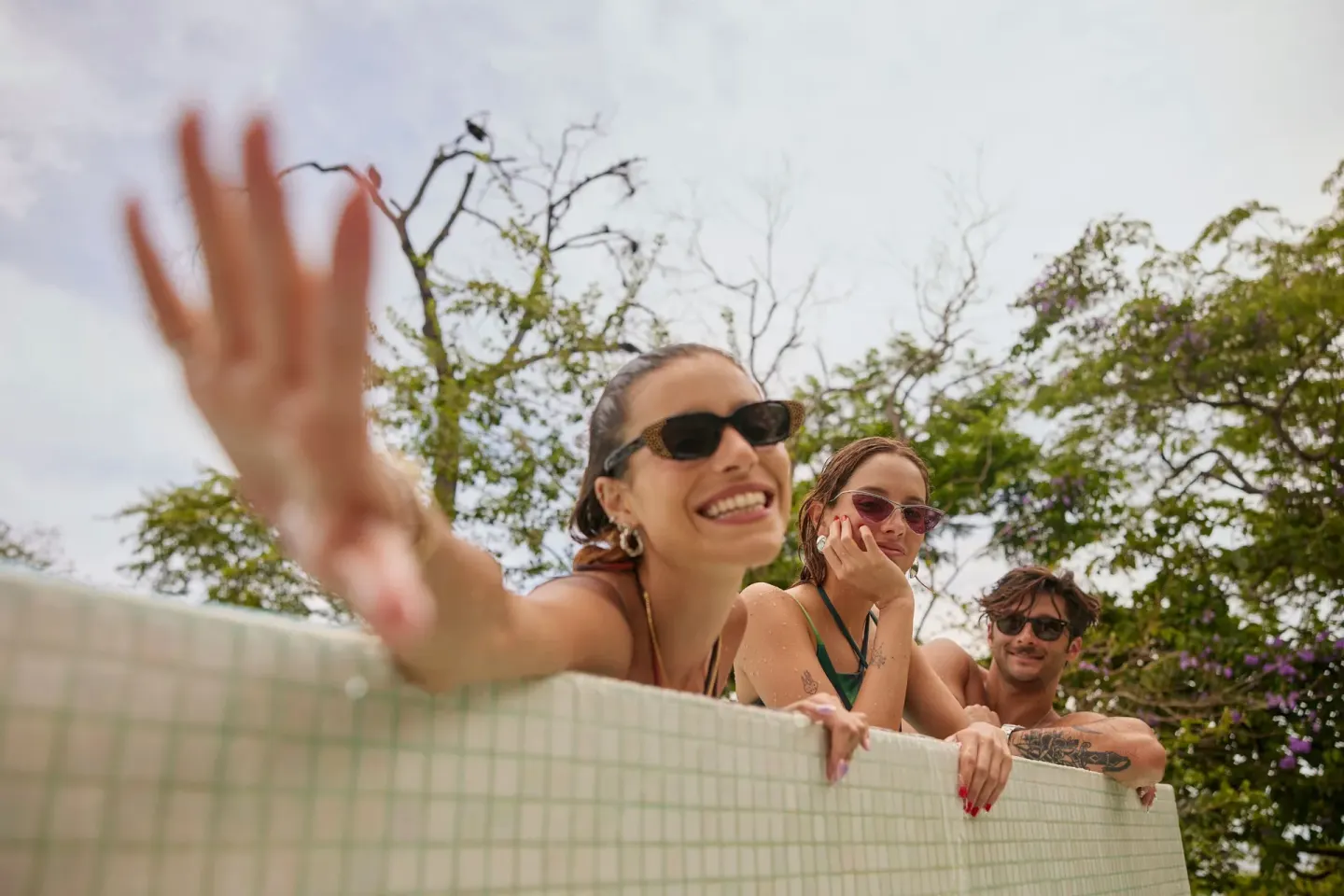 Guests lean over a tiled pool edge among trees at W Costa Rica - Reserva Conchal.