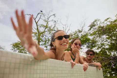 Guests lean over a tiled pool edge among trees at W Costa Rica - Reserva Conchal.