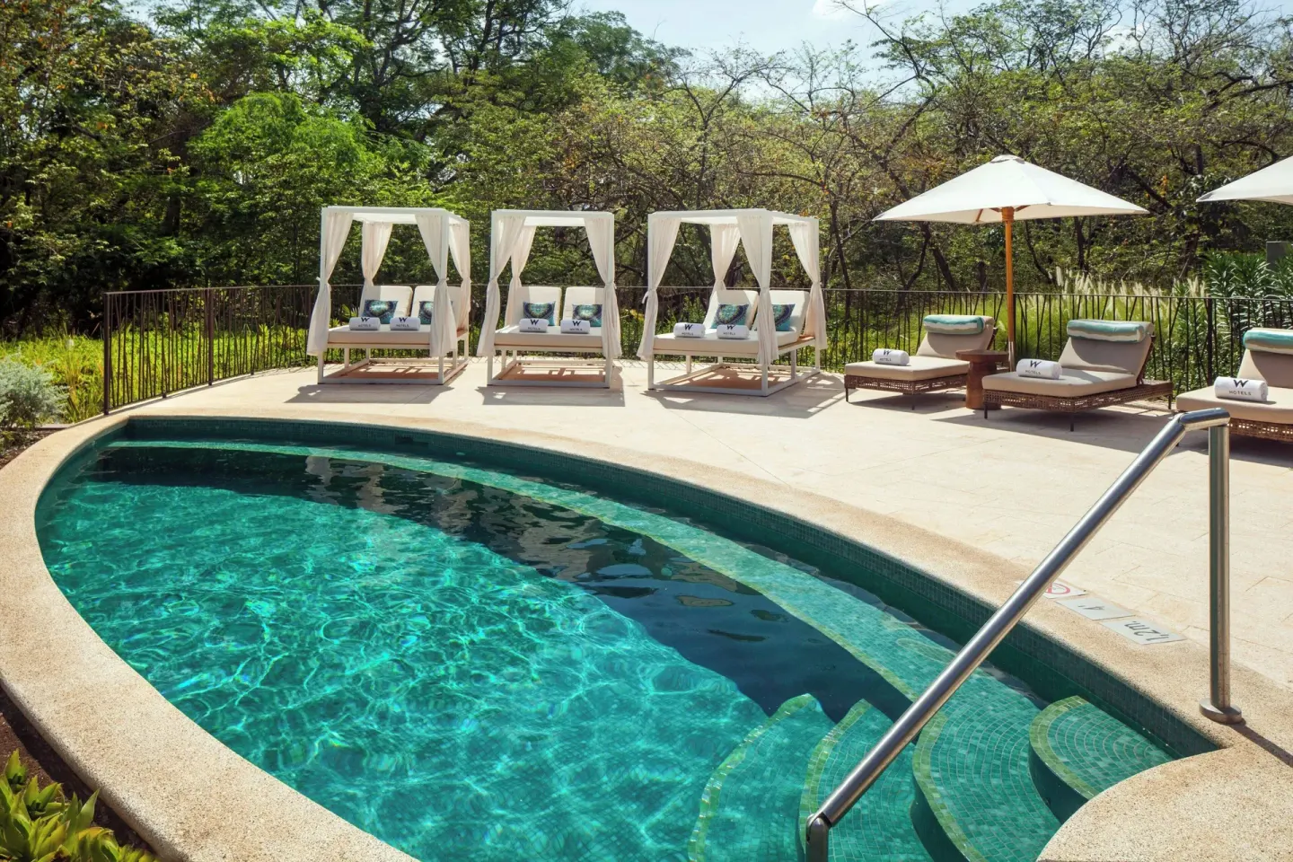 Small outdoor pool with cabanas and loungers at W Costa Rica - Reserva Conchal.