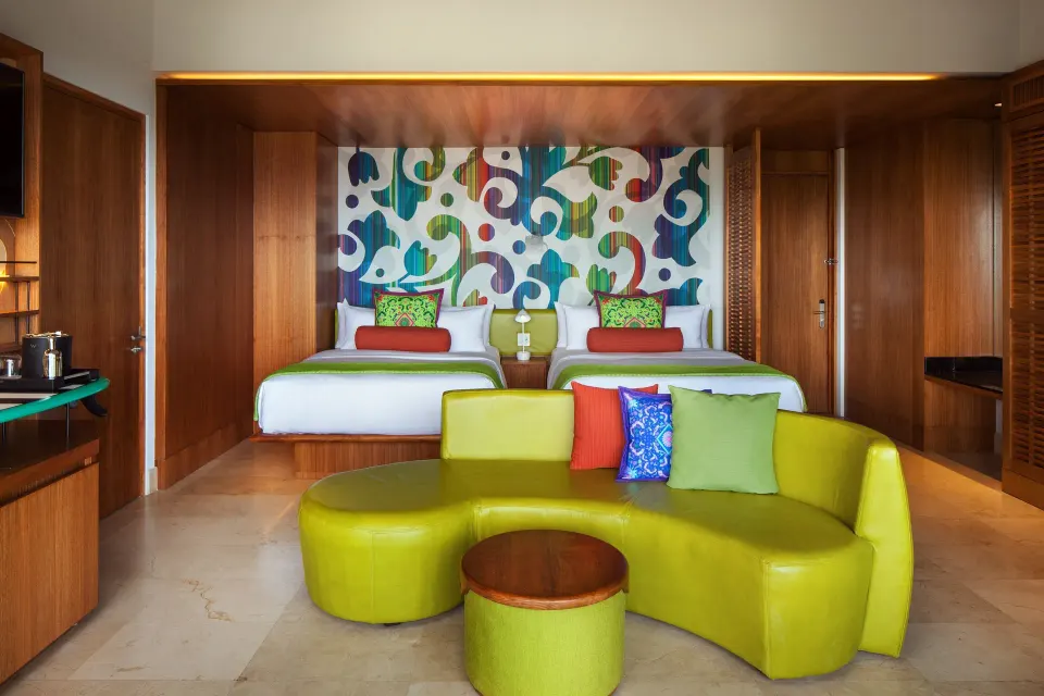 Deluxe Room balcony interior with two beds and green sofa at W Costa Rica - Reserva Conchal.