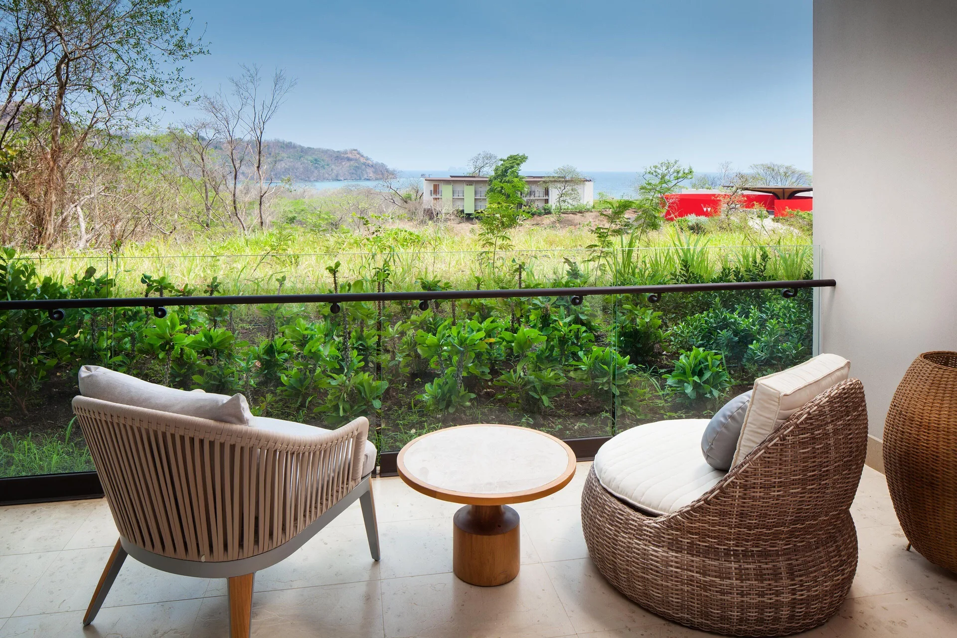Balcony seating with greenery and partial ocean view at W Costa Rica - Reserva Conchal.