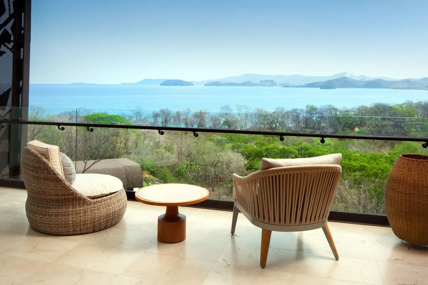 Premier Room Ocean View balcony with chairs, table and bay panorama at W Costa Rica - Reserva Conchal.