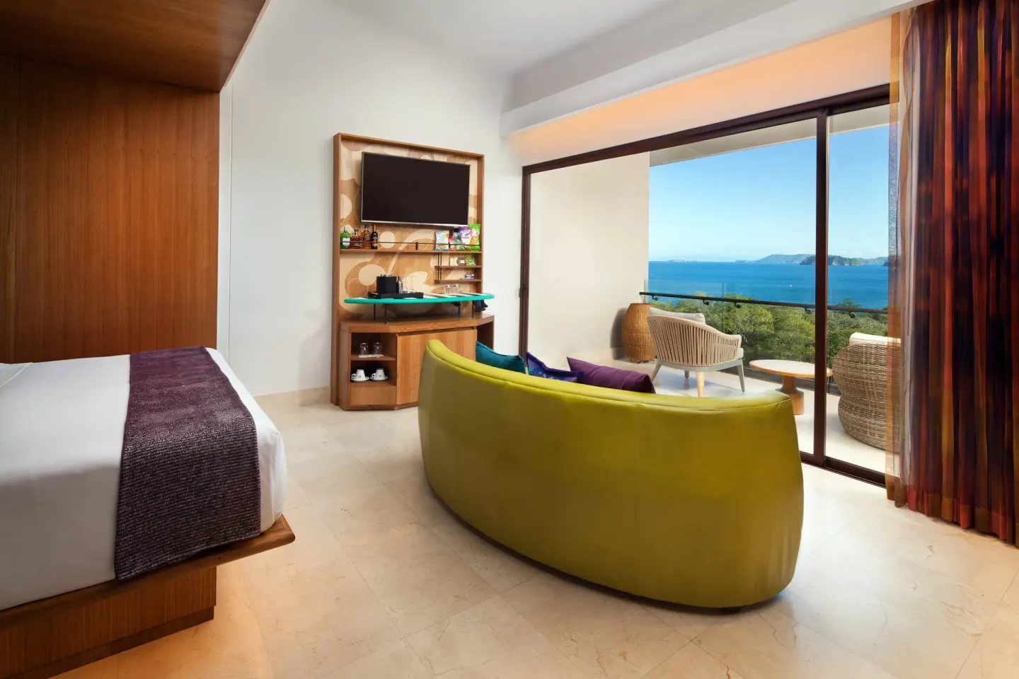 Premier Room with one bed, ocean-view balcony, curved sofa, and TV at W Costa Rica - Reserva Conchal.