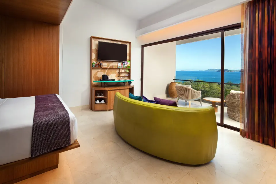 Premier Room with one bed, ocean-view balcony, curved sofa, and TV at W Costa Rica - Reserva Conchal.