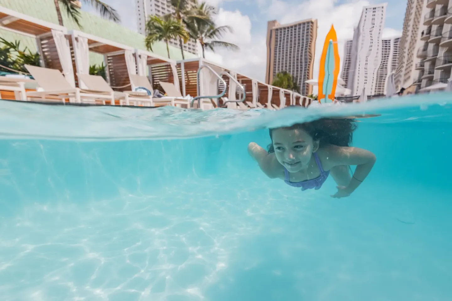 Child swimming underwater in the resort pool at Waikiki Beach Marriott Resort & Spa.