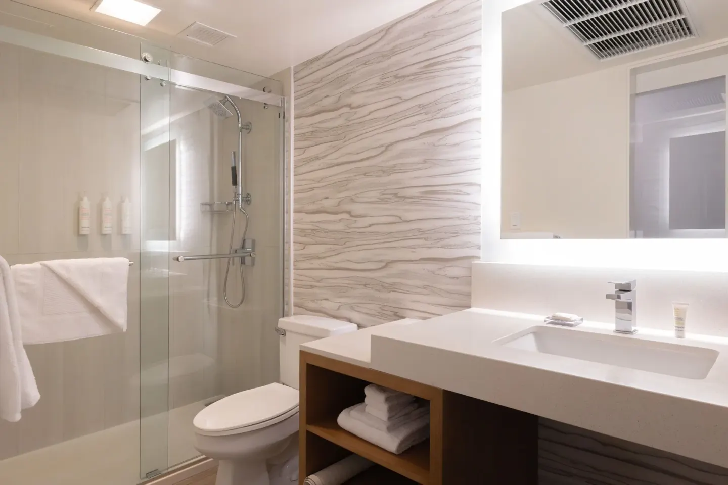 Compact bathroom with glass shower, sink vanity, and toilet at Waikiki Beach Marriott Resort & Spa.