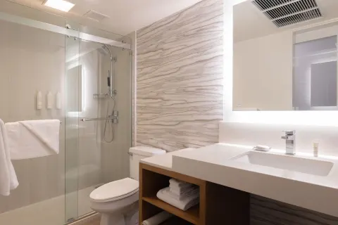 Compact bathroom with glass shower, sink vanity, and toilet at Waikiki Beach Marriott Resort & Spa.