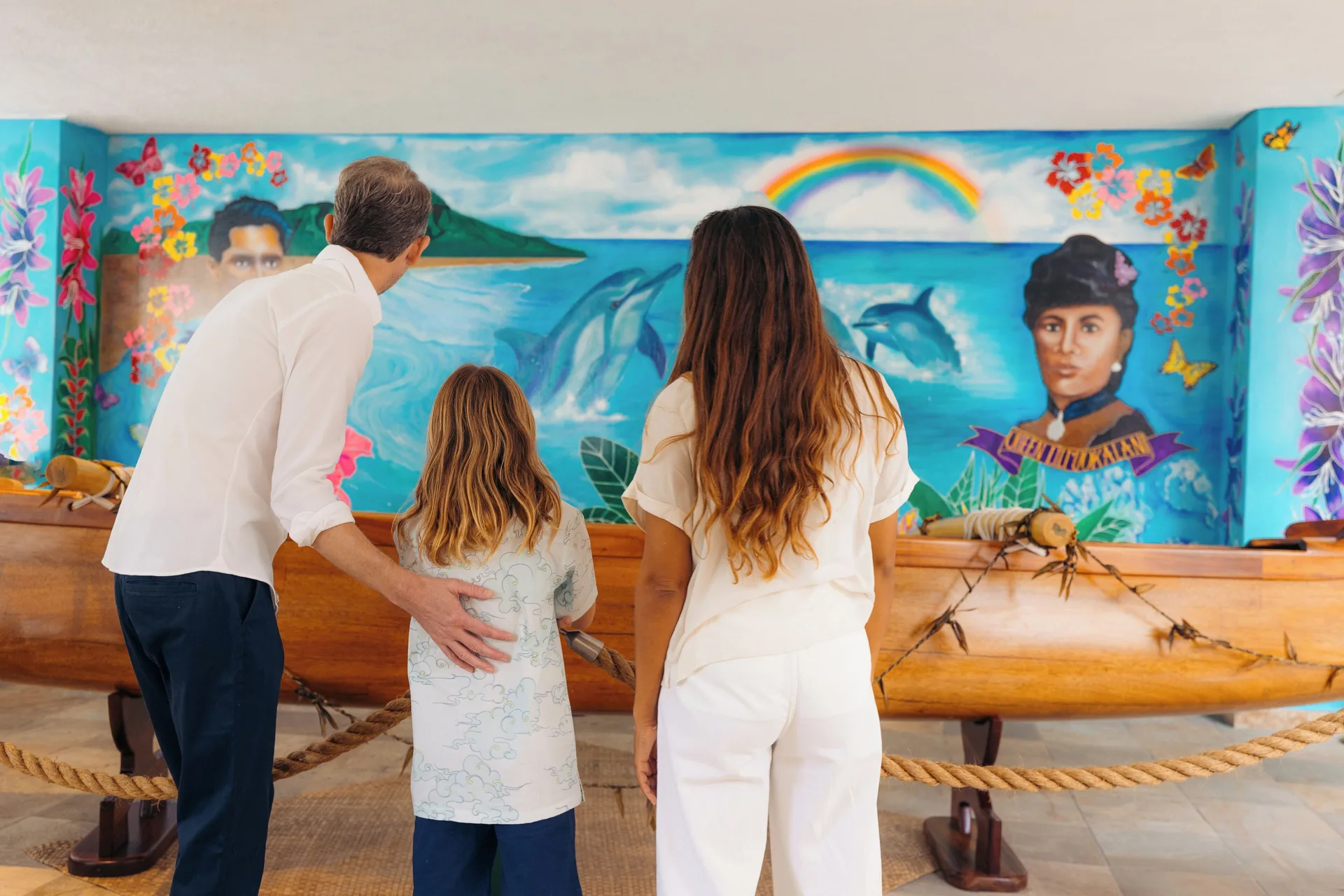 Family viewing a canoe and Hawaiian mural at Waikiki Beach Marriott Resort & Spa.