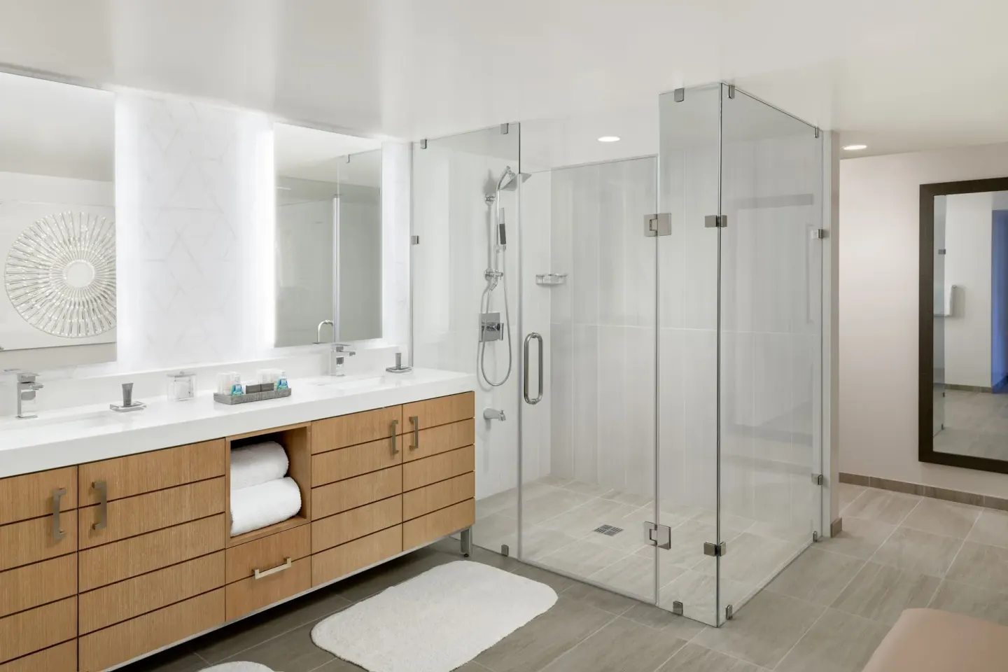 Guest bathroom with double vanity and glass walk-in shower at Waikiki Beach Marriott Resort & Spa.