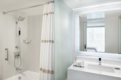 A bright bathroom with tub shower and vanity at Waikiki Beach Marriott Resort & Spa.