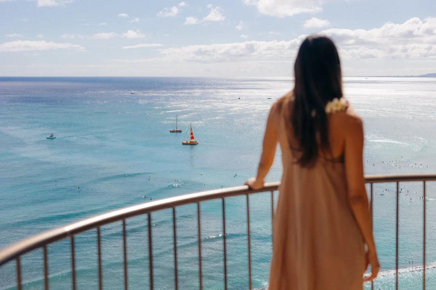 A guest stands on a balcony overlooking the ocean at Waikiki Beach Marriott Resort & Spa.