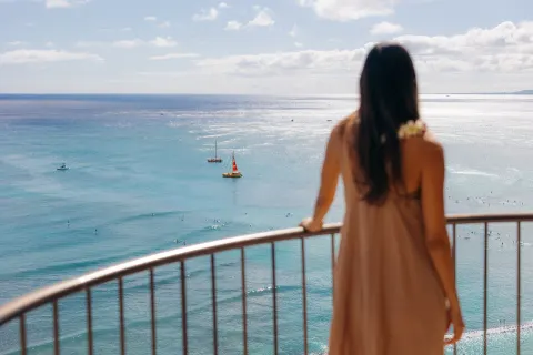 A guest stands on a balcony overlooking the ocean at Waikiki Beach Marriott Resort & Spa.