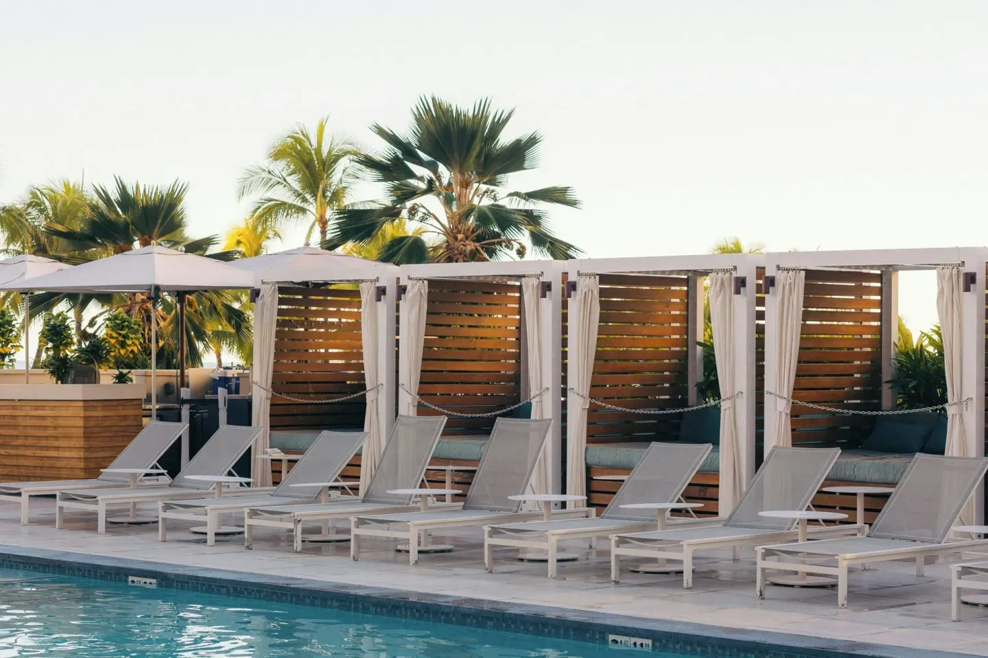 Pool cabanas and loungers beside palms at Waikiki Beach Marriott Resort & Spa.