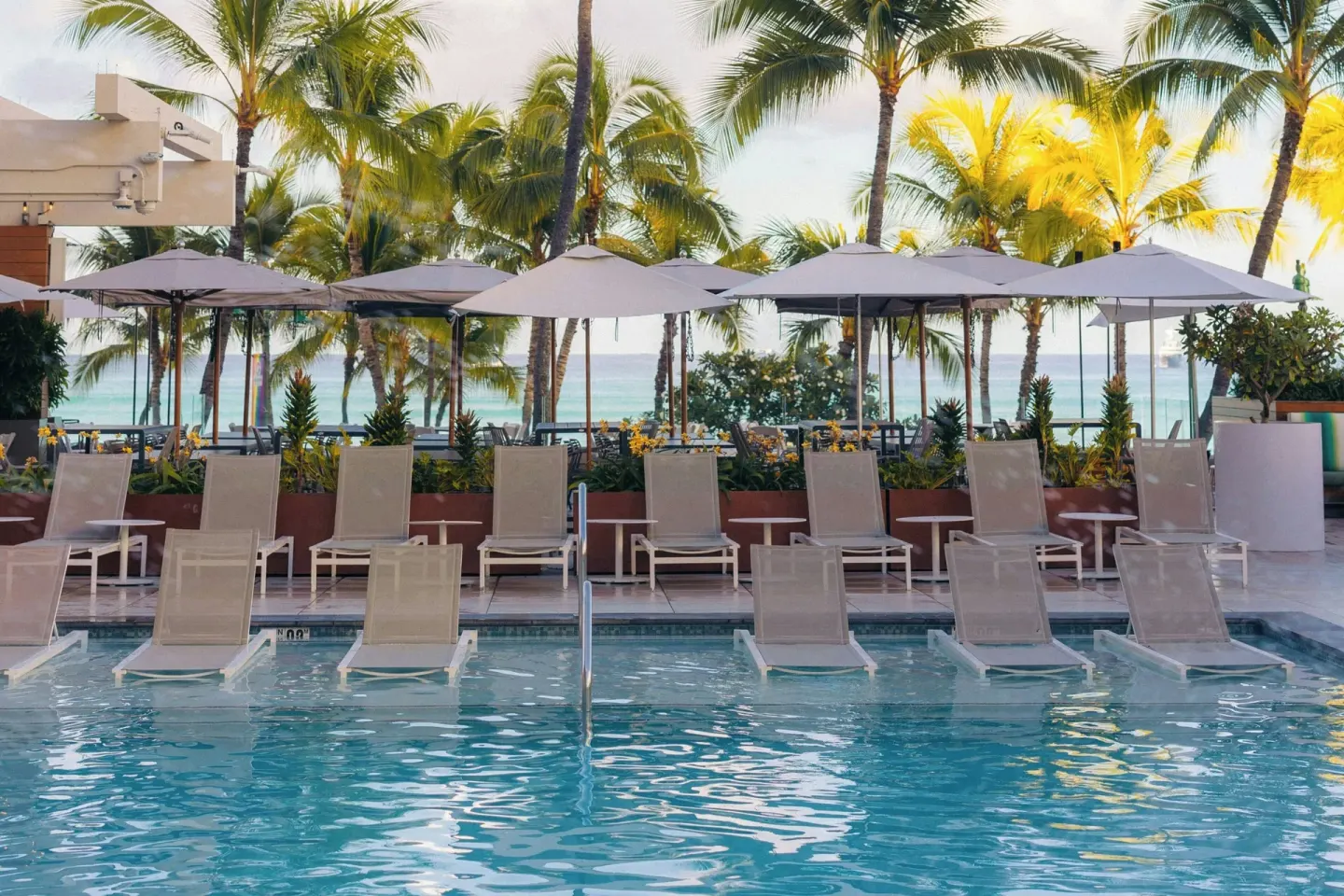Pool loungers and umbrellas facing the ocean at Waikiki Beach Marriott Resort & Spa.