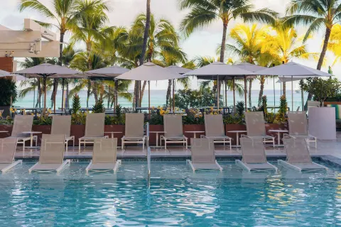 Pool loungers and umbrellas facing the ocean at Waikiki Beach Marriott Resort & Spa.