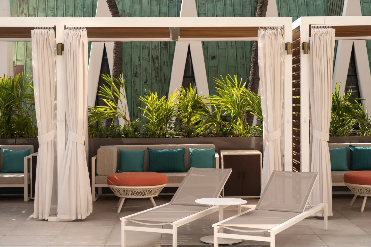 Poolside cabanas with loungers and tropical plants at Waikiki Beach Marriott Resort & Spa.