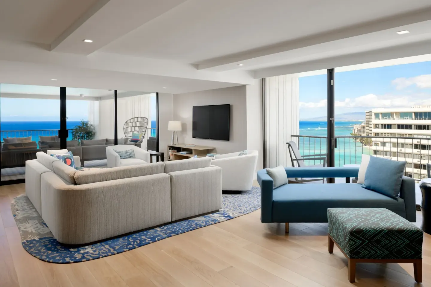 A suite living room with ocean views and a blue chaise at Waikiki Beach Marriott Resort & Spa.