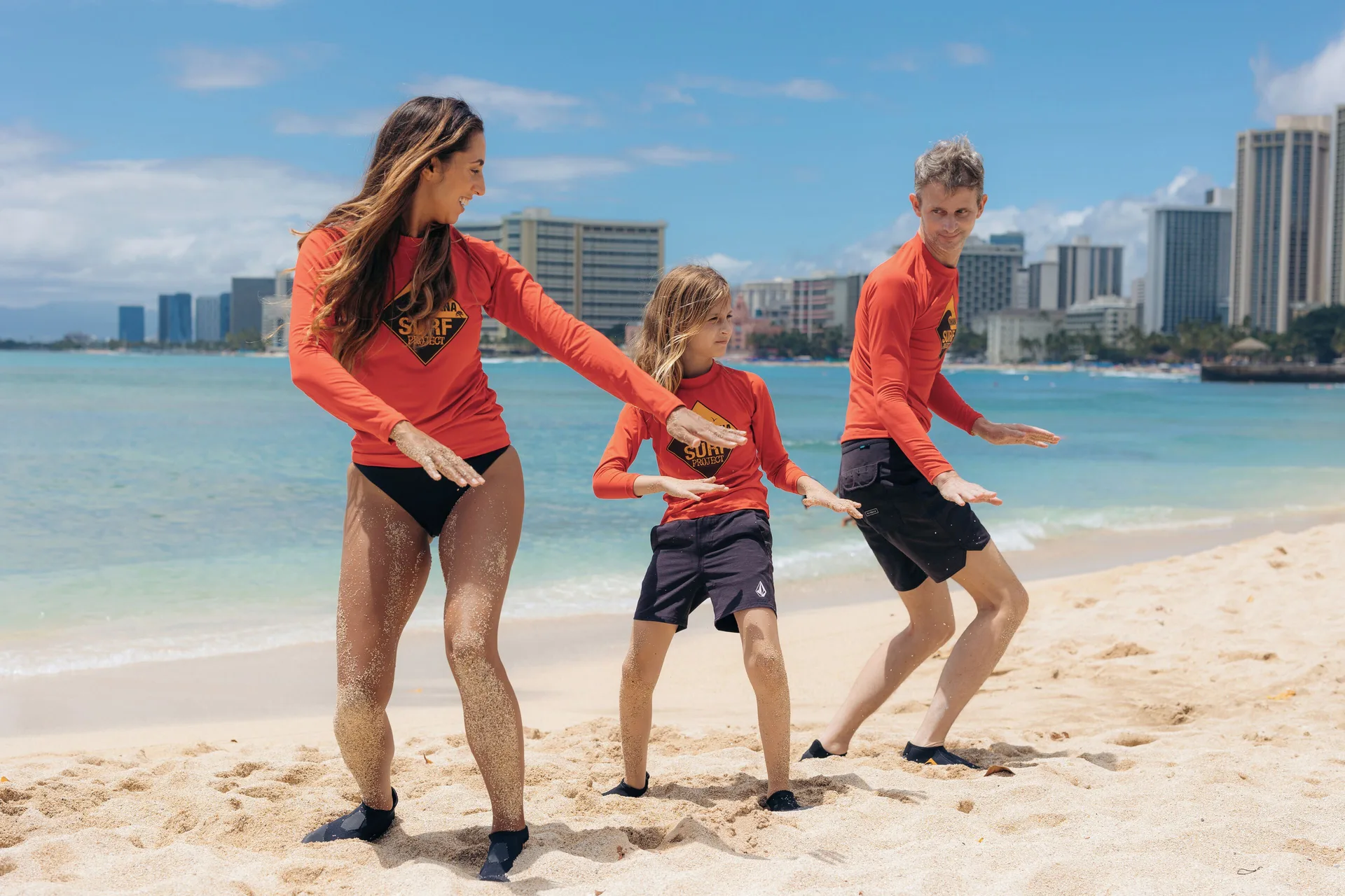 Family practicing surf motions on Waikiki Beach Marriott Resort & Spa near Waikiki Beach Marriott Resort & Spa.