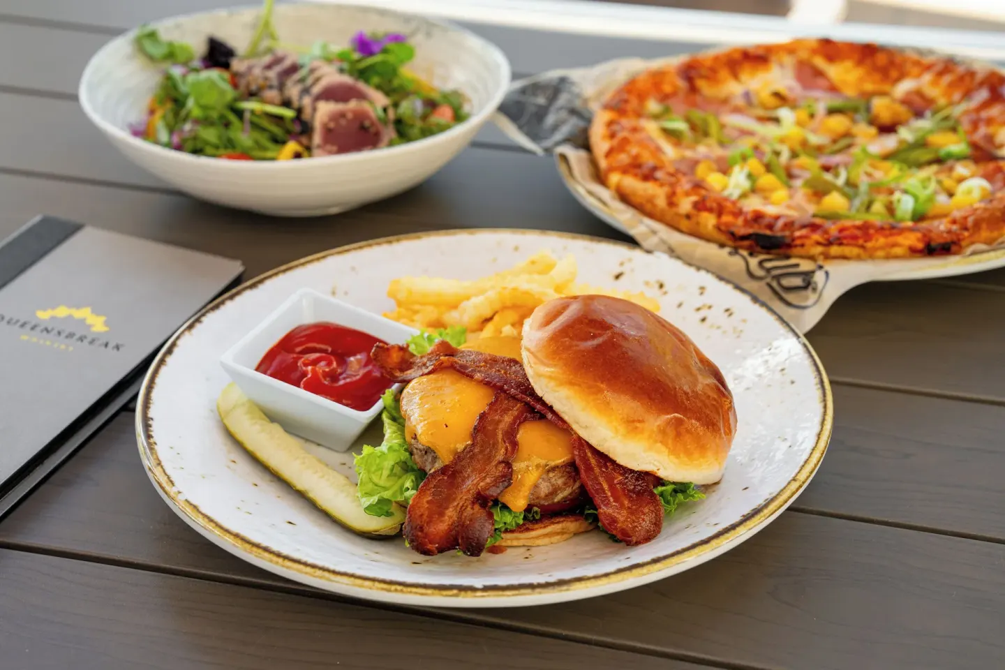 Burger, pizza, and salad are served on a table at Waikiki Beach Marriott Resort & Spa.