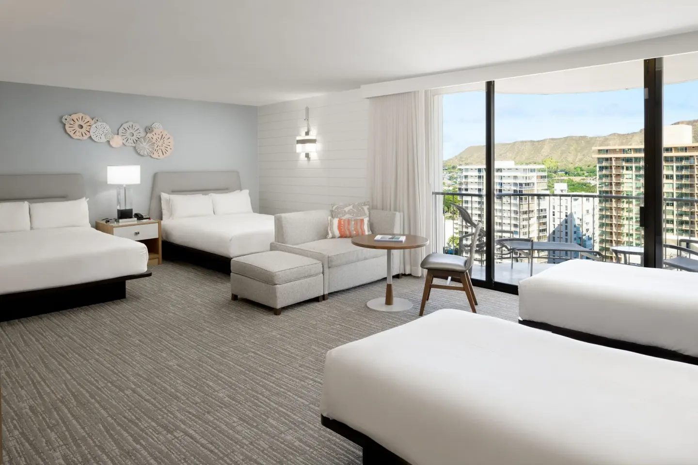 Family junior suite with four beds, sofa seating and balcony at Waikiki Beach Marriott Resort & Spa.