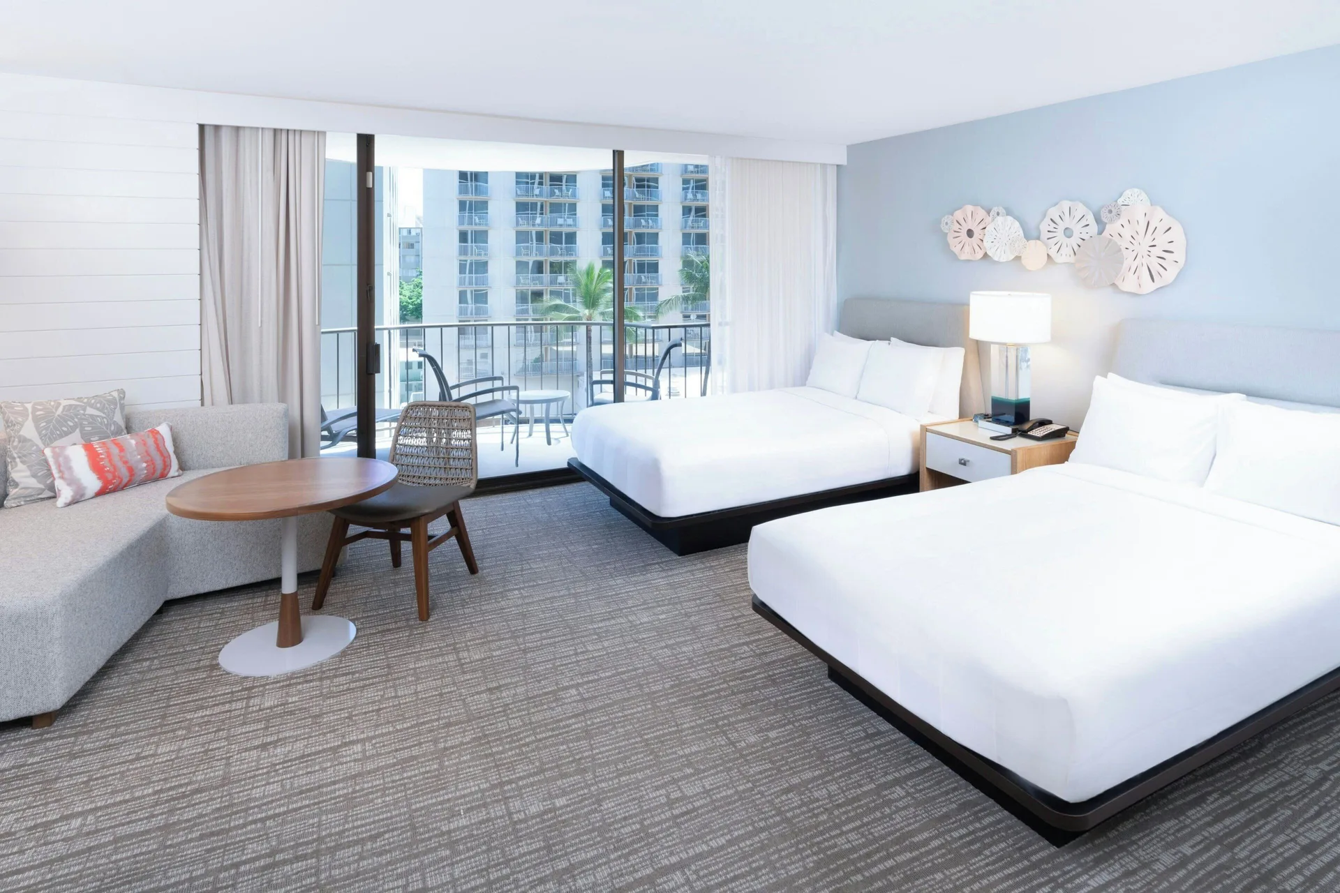 Two-bed balcony room with sofa and city-facing glass doors at Waikiki Beach Marriott Resort & Spa.