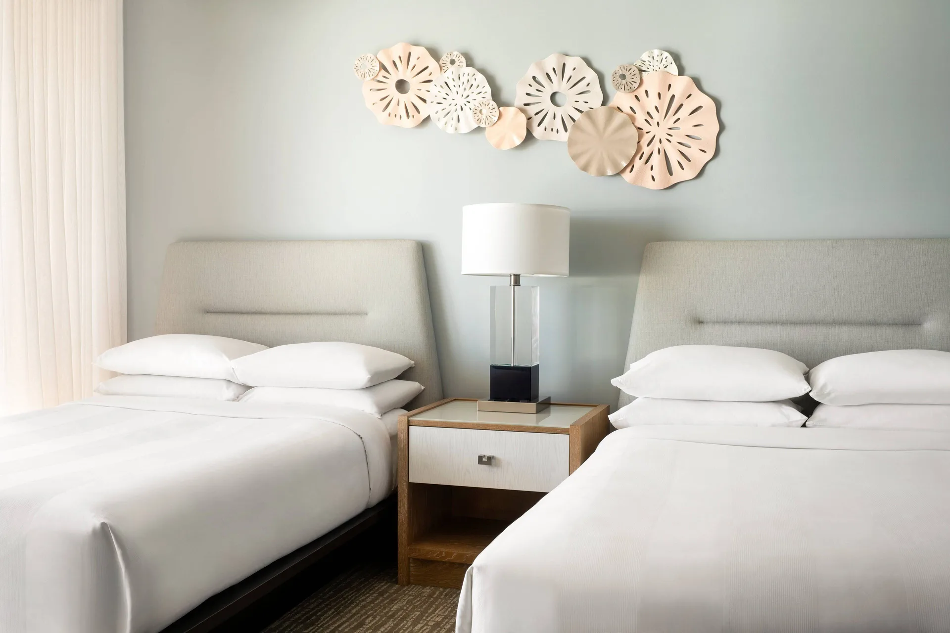 Two beds with pale headboards and wall art at Waikiki Beach Marriott Resort & Spa.