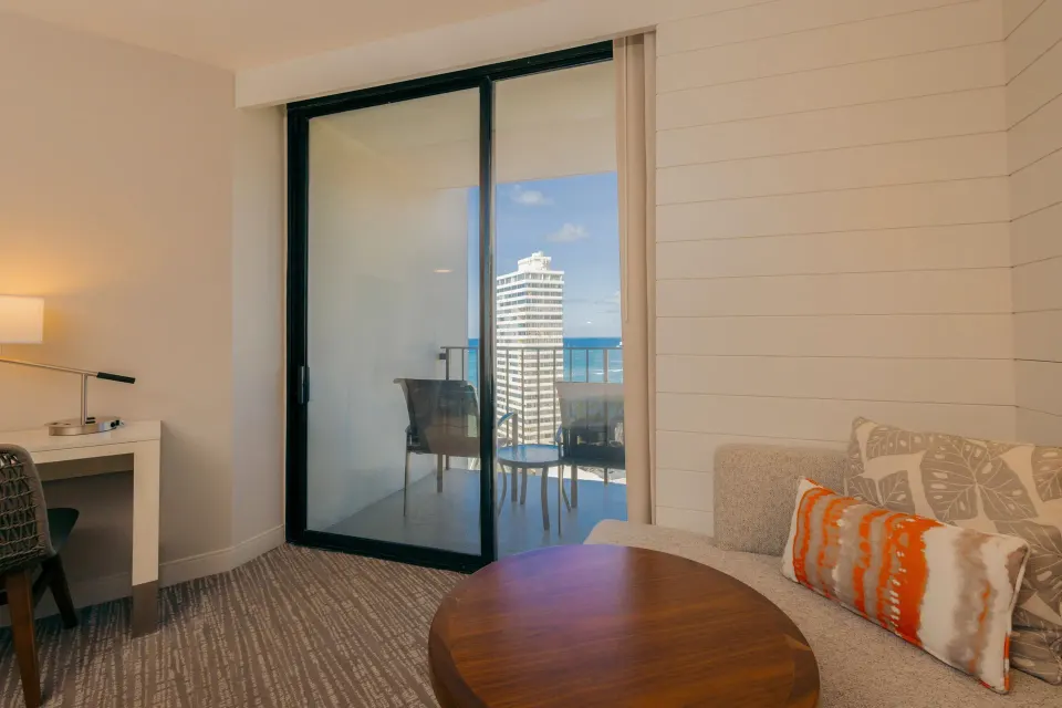 Sofa seating and balcony doors in a Paoakalani Ocean View room at Waikiki Beach Marriott Resort & Spa.