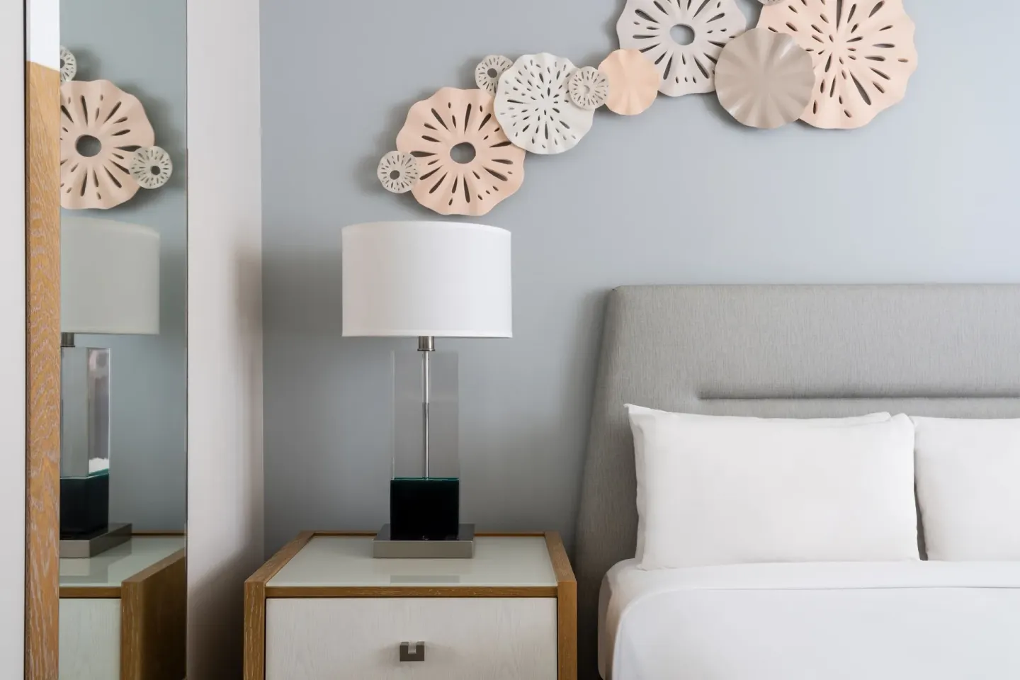 Guest room bed and nightstand at Waikiki Beach Marriott Resort & Spa with wall art and bedside lamp.