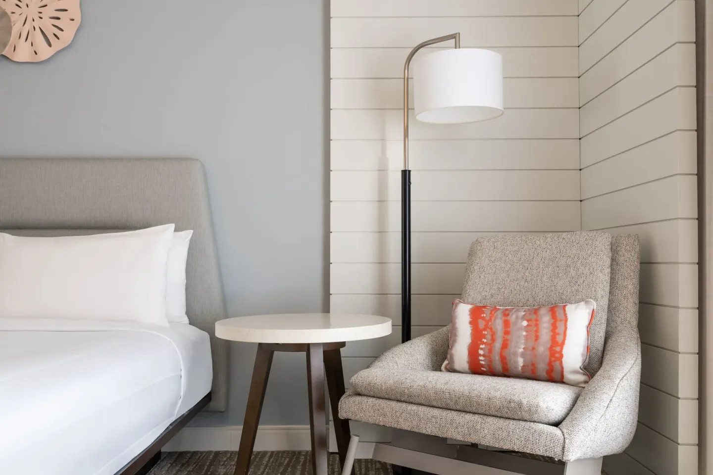 Guest room seating area at Waikiki Beach Marriott Resort & Spa with bed, chair, table, and floor lamp.