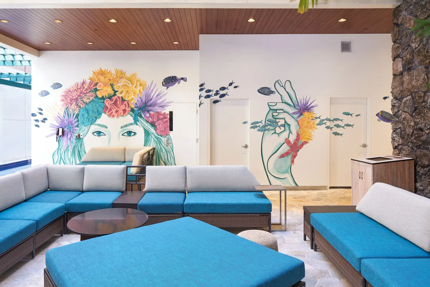 Covered lounge seating with blue cushions and mural artwork at Waikiki Malia.