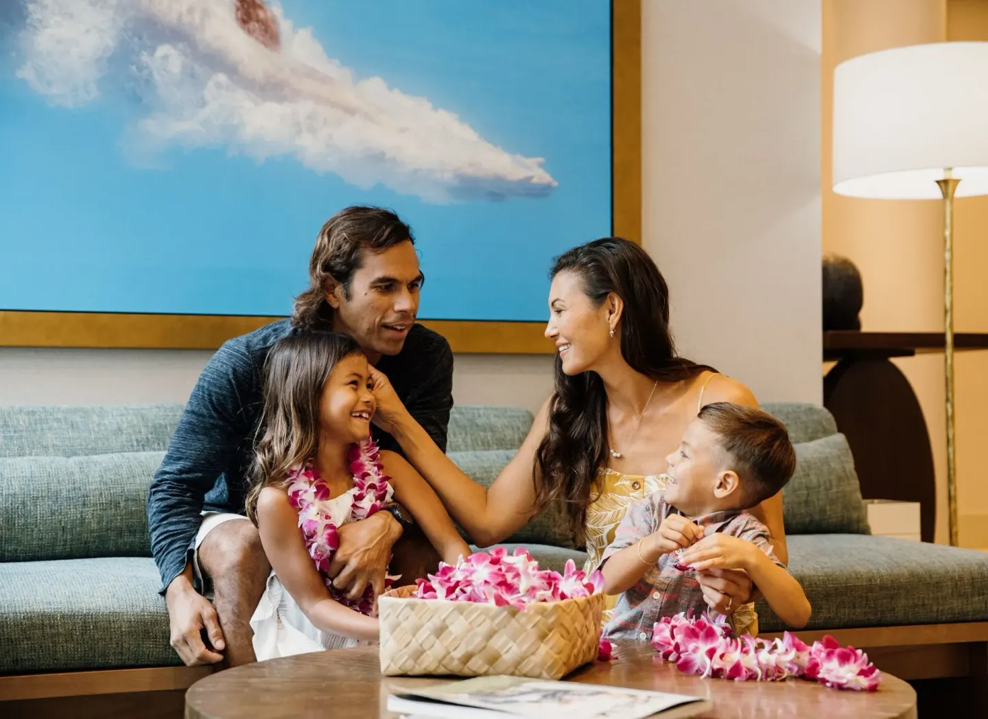 A family sits on a lobby sofa with flower leis at Waikiki Malia.