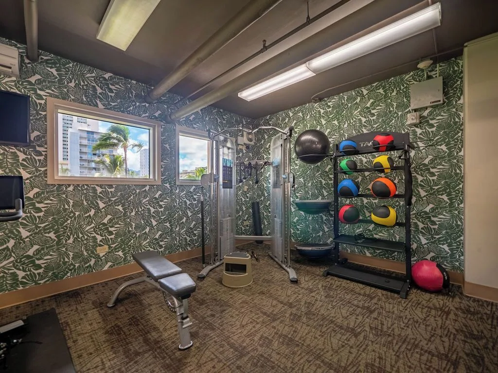 Fitness room with cable machine, bench, and medicine balls at Waikiki Malia.