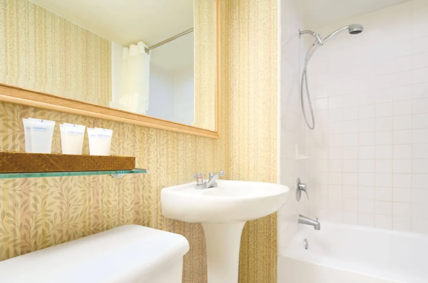 Bathroom with pedestal sink, mirror, amenities, and tub shower at Waikiki Malia.
