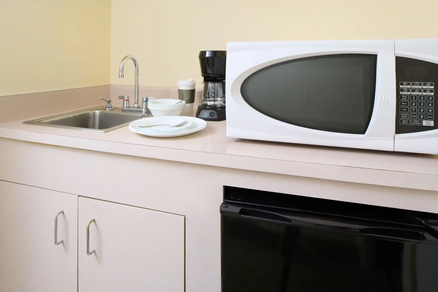 Guest room kitchenette with sink, microwave, coffee maker, and mini fridge at Waikiki Malia.